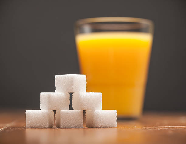 A glass of orange juice with a stack of sugar blocks
